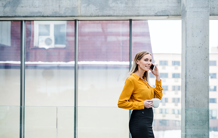 Young woman on the phone with a coffee in her hand
