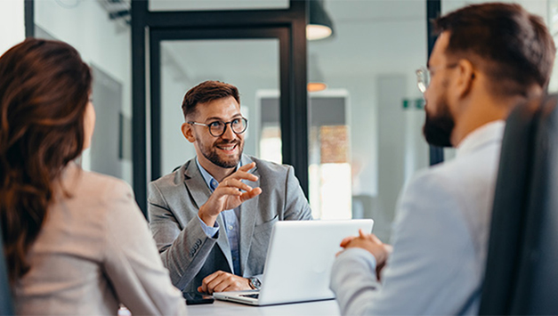 Three employees chatting at a desk in the office