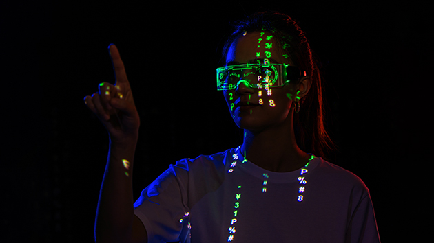 Frau mit Augmented Reality (AR) Brille steht im Dunkeln und arbeitet