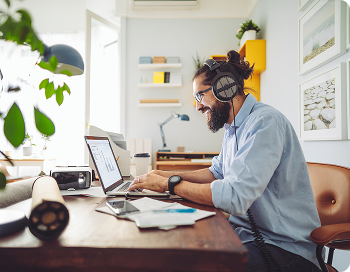 Young man sitting at his laptop in his home office, working with motivation